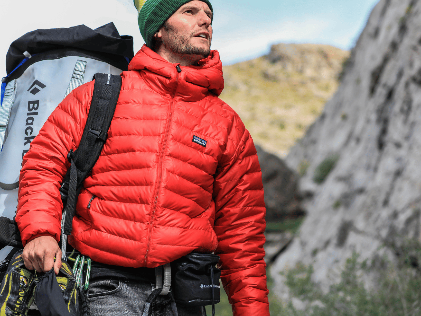 A climber in a red Patagonia jacket stands outdoors, evoking a sense of rugged adventure and conscious consumerism.