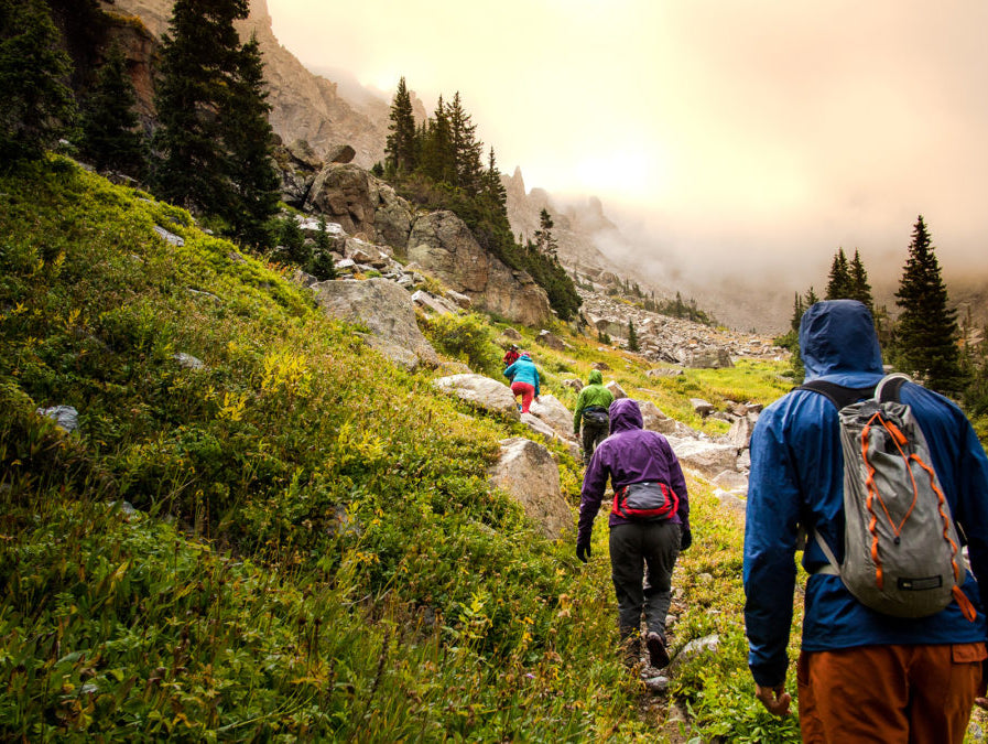 A group of hikers trek up a misty mountain trail, conveying a sense of adventure and shared outdoor experience.