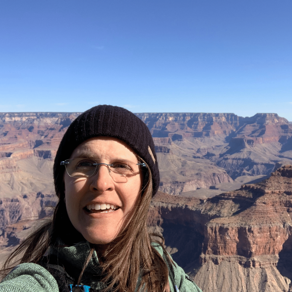 Carey smiles in front of the Grand Canyon, her black beanie hinting at a cool, adventurous day.