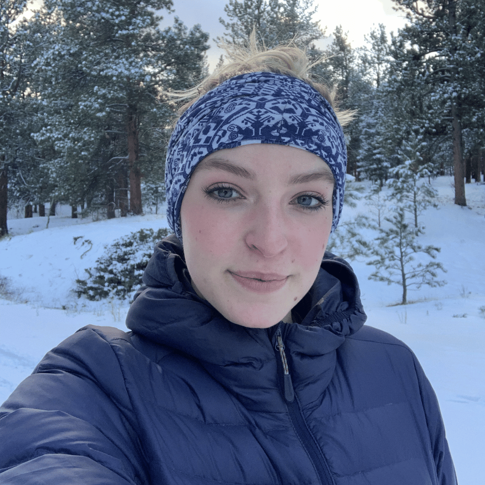 A winter selfie of Lowry Miller with a snowy forest backdrop, conveying a sense of peace and appreciation for nature.