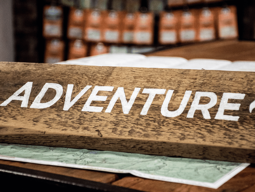 A rustic wooden sign with "Adventure" painted in white evokes a spirit of exploration and resilience.