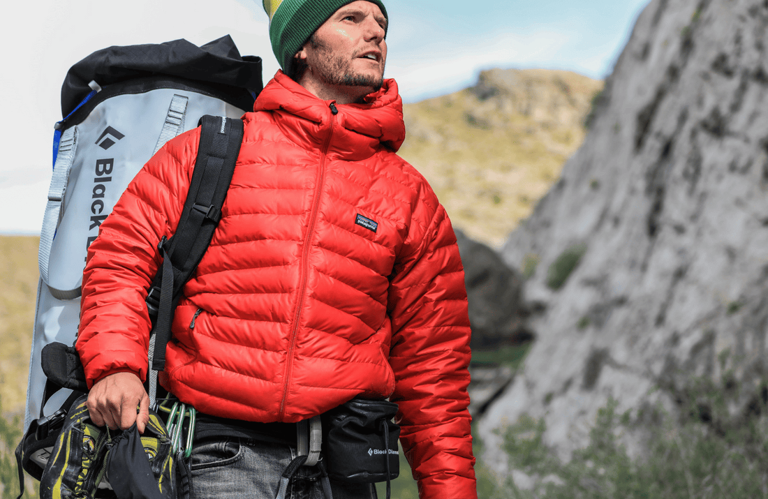 A climber in a red Patagonia jacket stands outdoors, evoking a sense of rugged adventure and conscious consumerism.
