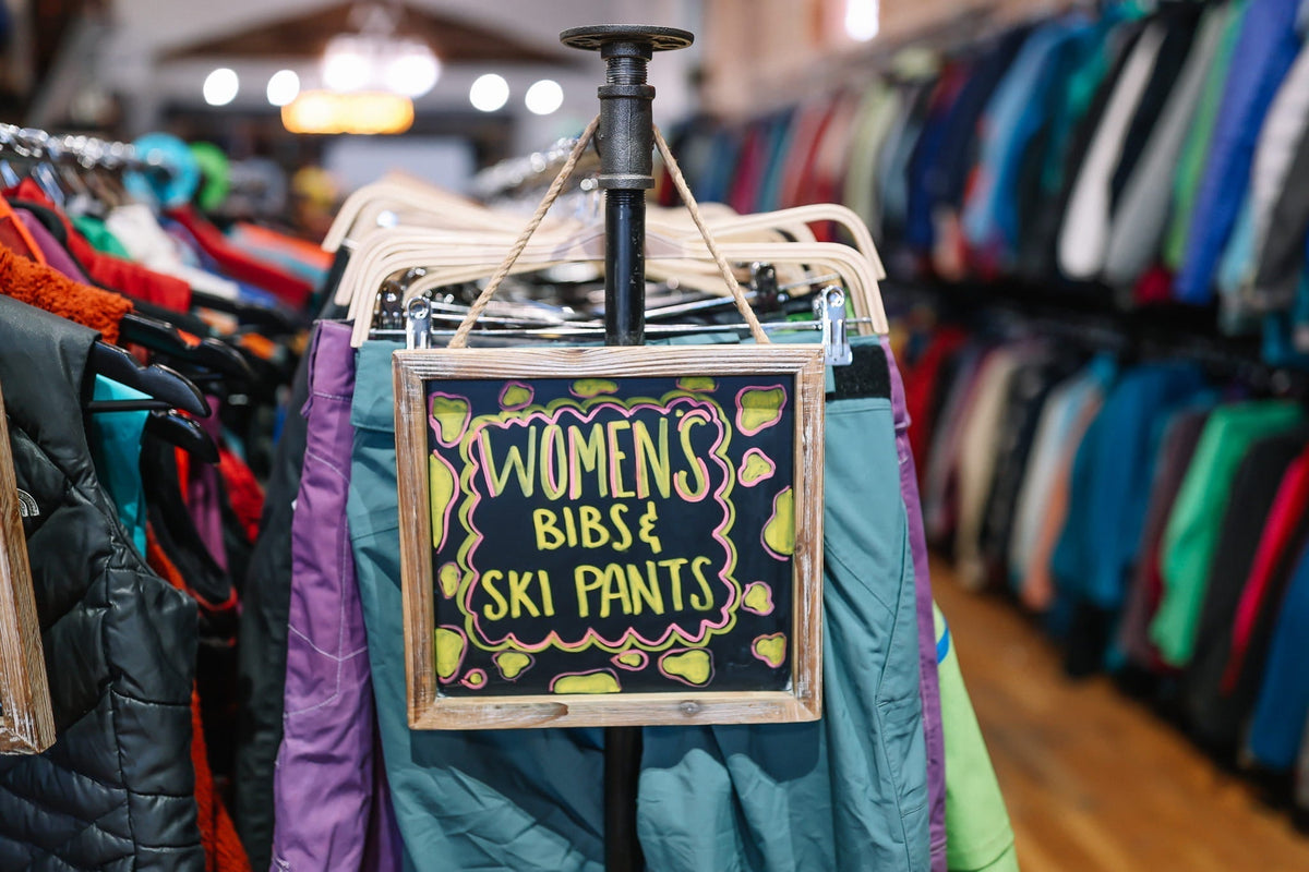 A section of used women's ski pants and ski bibs.