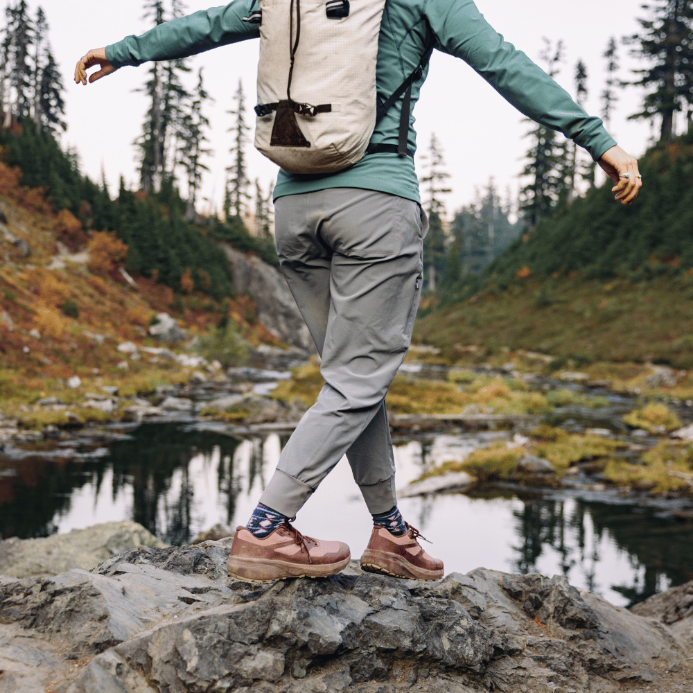 Person hiking by a lake with a backpack in a forest setting