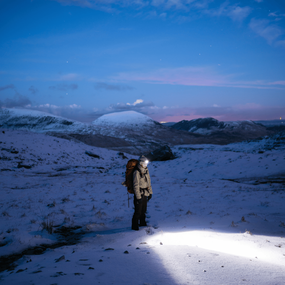 Nighttime hiking scene with a person wearing a headlamp, evoking adventure and the need for reliable lighting.

