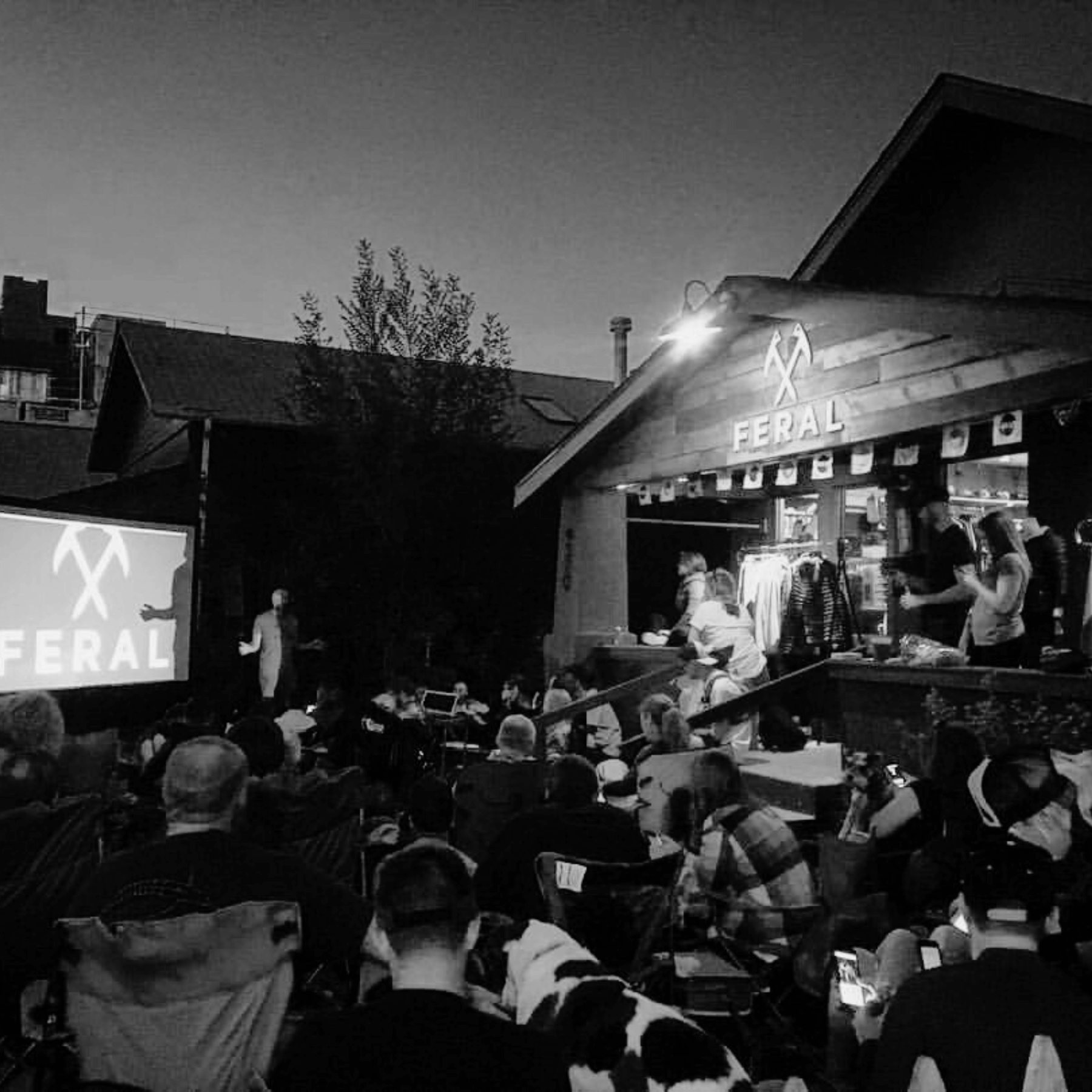 Outdoor event with a crowd watching a screen, featuring the 'Feral' brand.