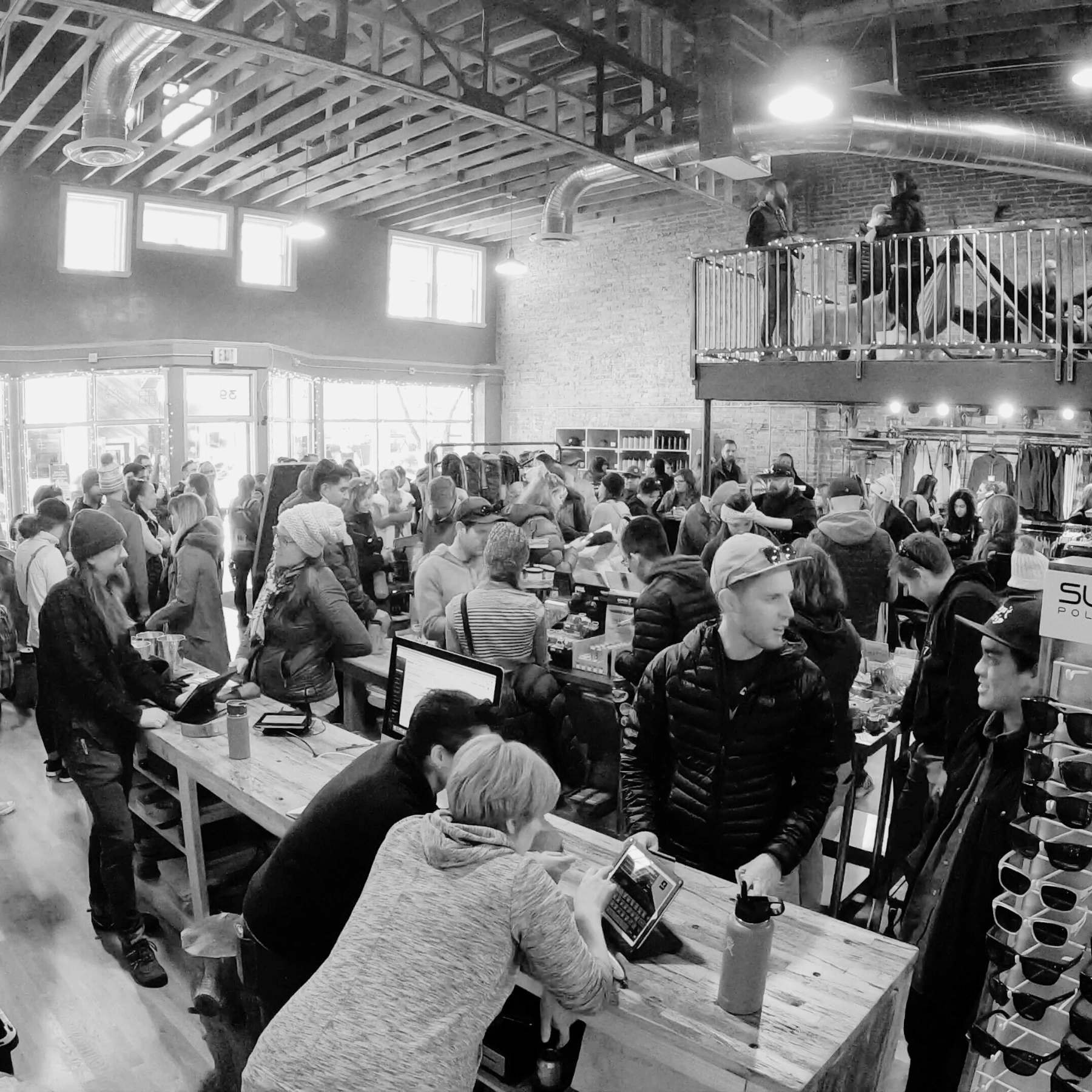 Black and white photo of a crowded indoor event with people around tables.