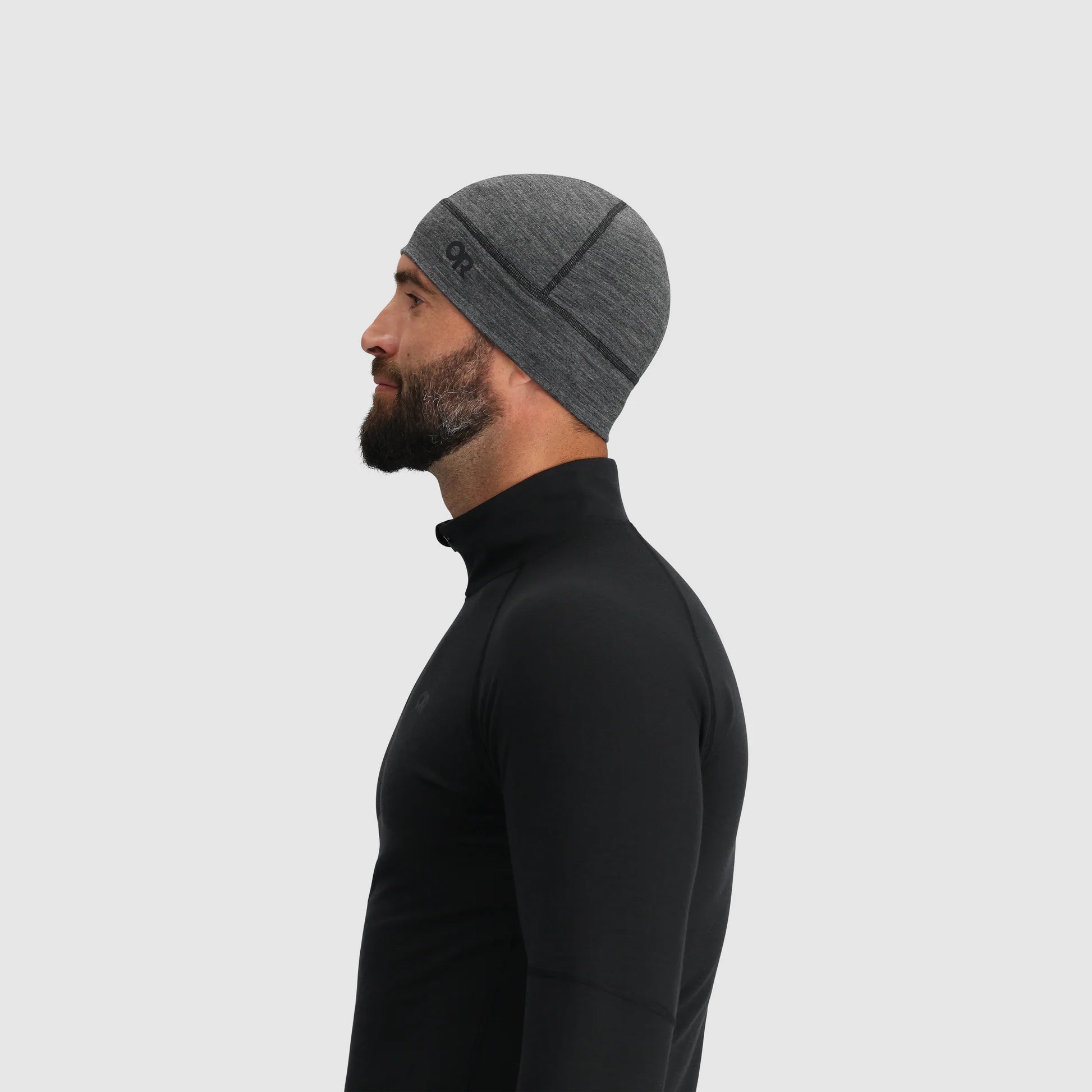 Gray merino wool beanie by Outdoor Research with horizontal stripe pattern, shown in side view with black quarter-zip top.