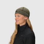 Green wool beanie by Outdoor Research, with visible seam detail, worn by a blonde woman in a black jacket.