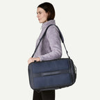 Blue backpack by Patagonia, slung over the shoulder, worn with a lavender fleece top.
