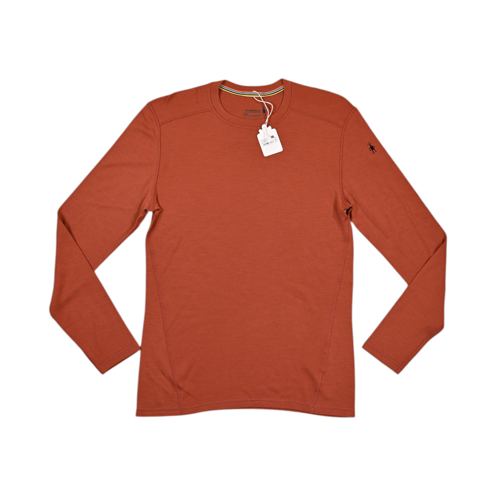Rust-orange crew neck baselayer by Smartwool, laid flat with hangtag attached.