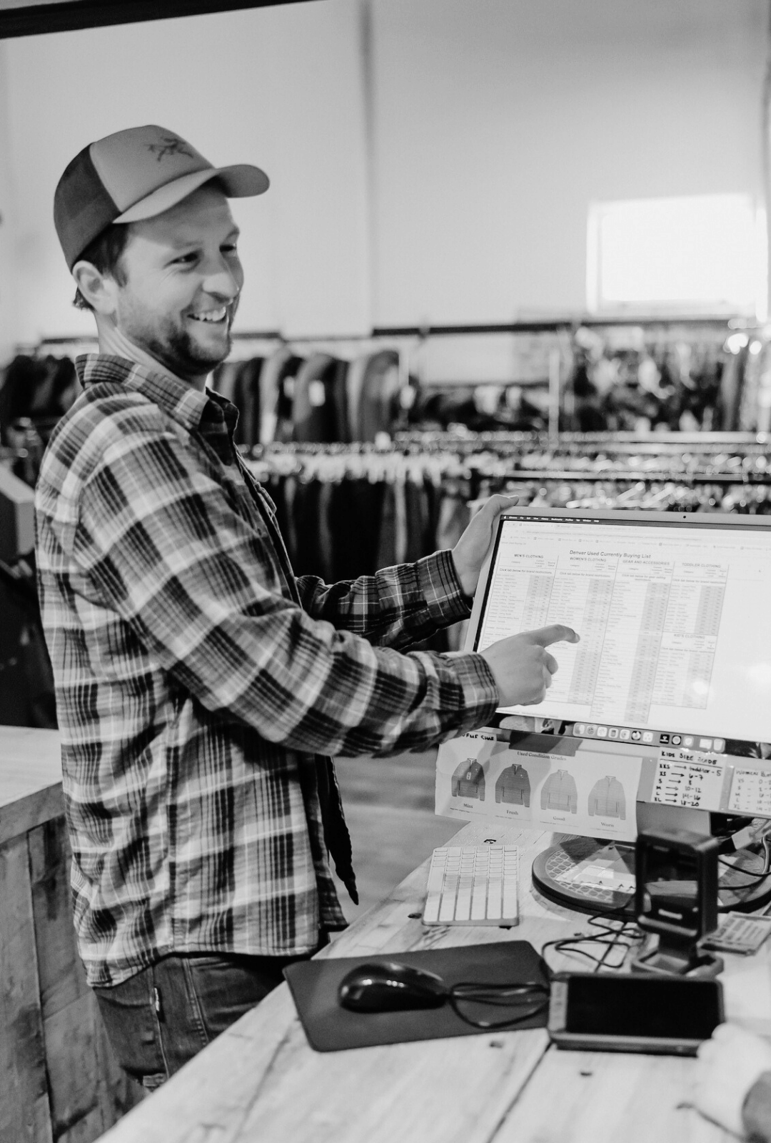 Man in plaid shirt and cap using a computer in a store setting
