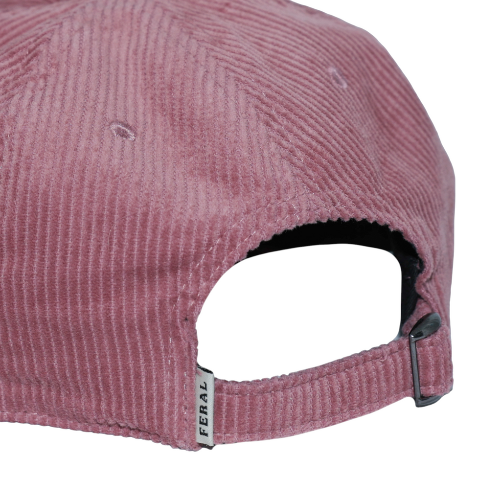 Dusty rose corduroy hat by FERAL, showing the adjustable back strap and logo tag.