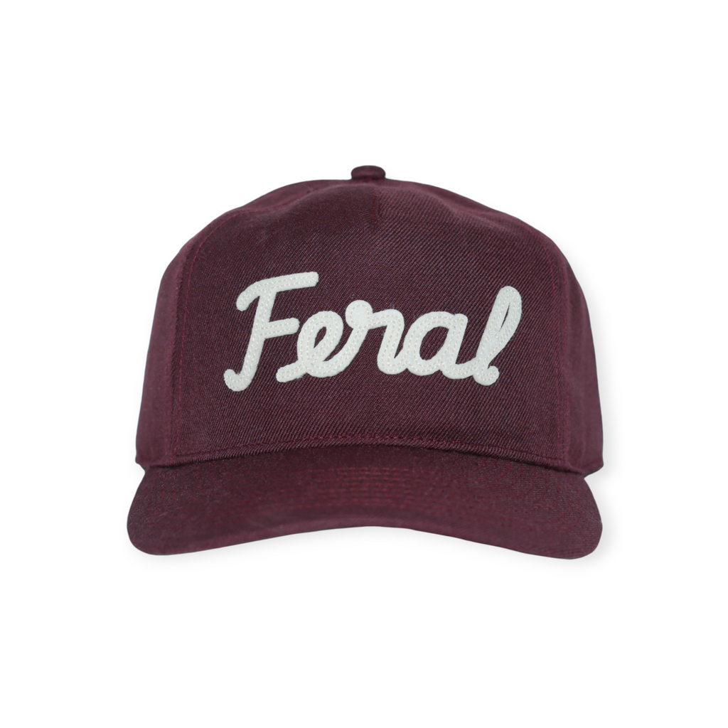 Burgundy wool hat by FERAL with a white, cursive "Feral" logo on the front.