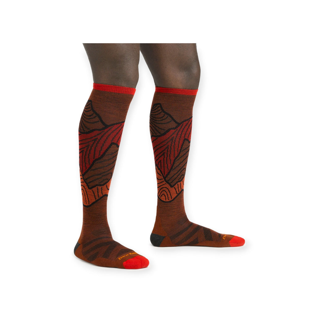Brown over-the-calf socks by Darn Tough, featuring red accents and mountain-inspired graphic pattern details.