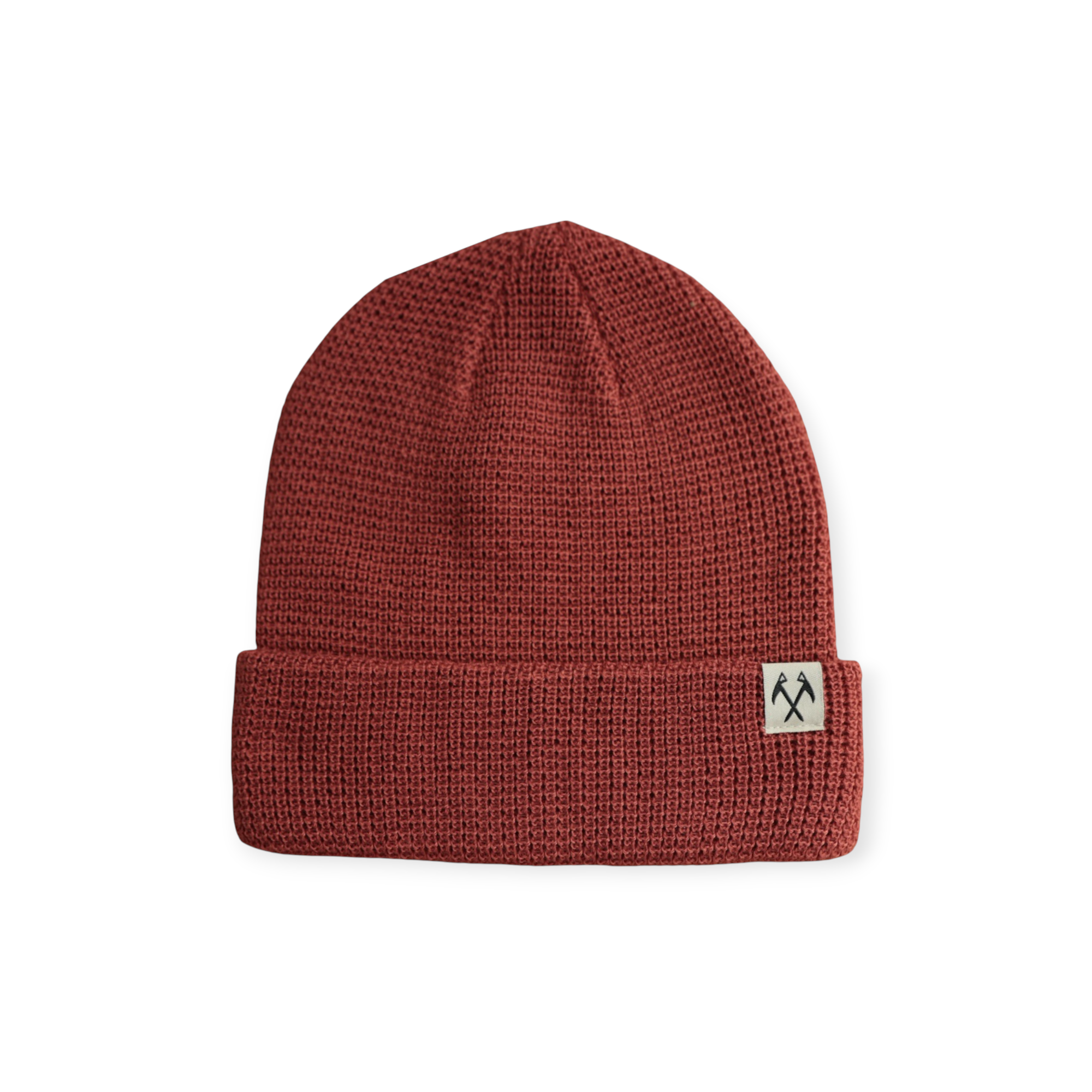 Rust-colored knit beanie by FERAL, with a textured waffle pattern and a small logo tag on the brim.
