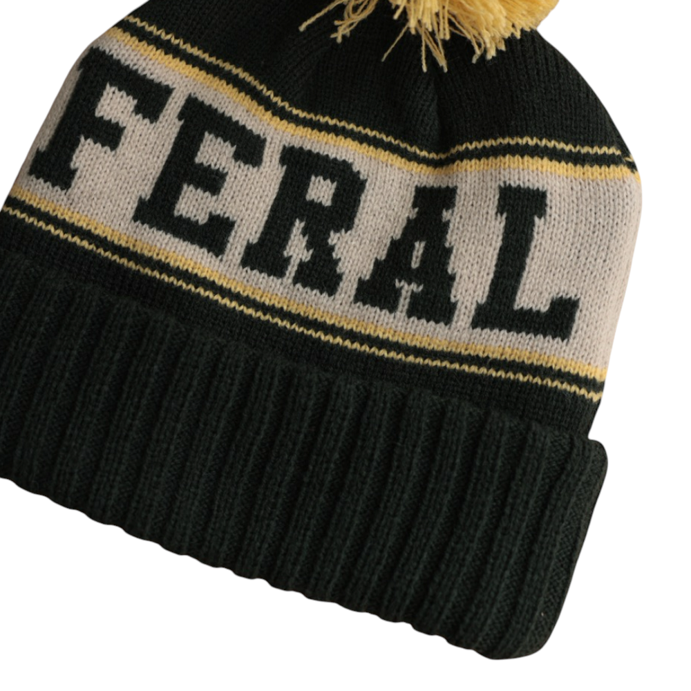 Dark green knit beanie by FERAL with a gray stripe containing the word "FERAL" in dark green letters, topped with a yellow pompom.