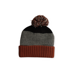 Knit beanie by FERAL, with multicolored pompom, herringbone pattern, and ribbed brim.