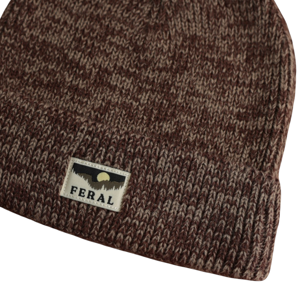 Brown knit beanie by FERAL, featuring a melange yarn texture and a fabric logo patch.
