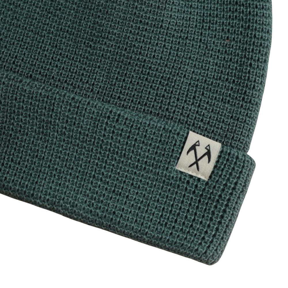 Green knit beanie by FERAL with a textured waffle pattern and folded brim.