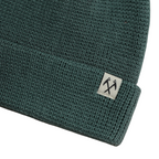 Green knit beanie by FERAL with a textured waffle pattern and folded brim.