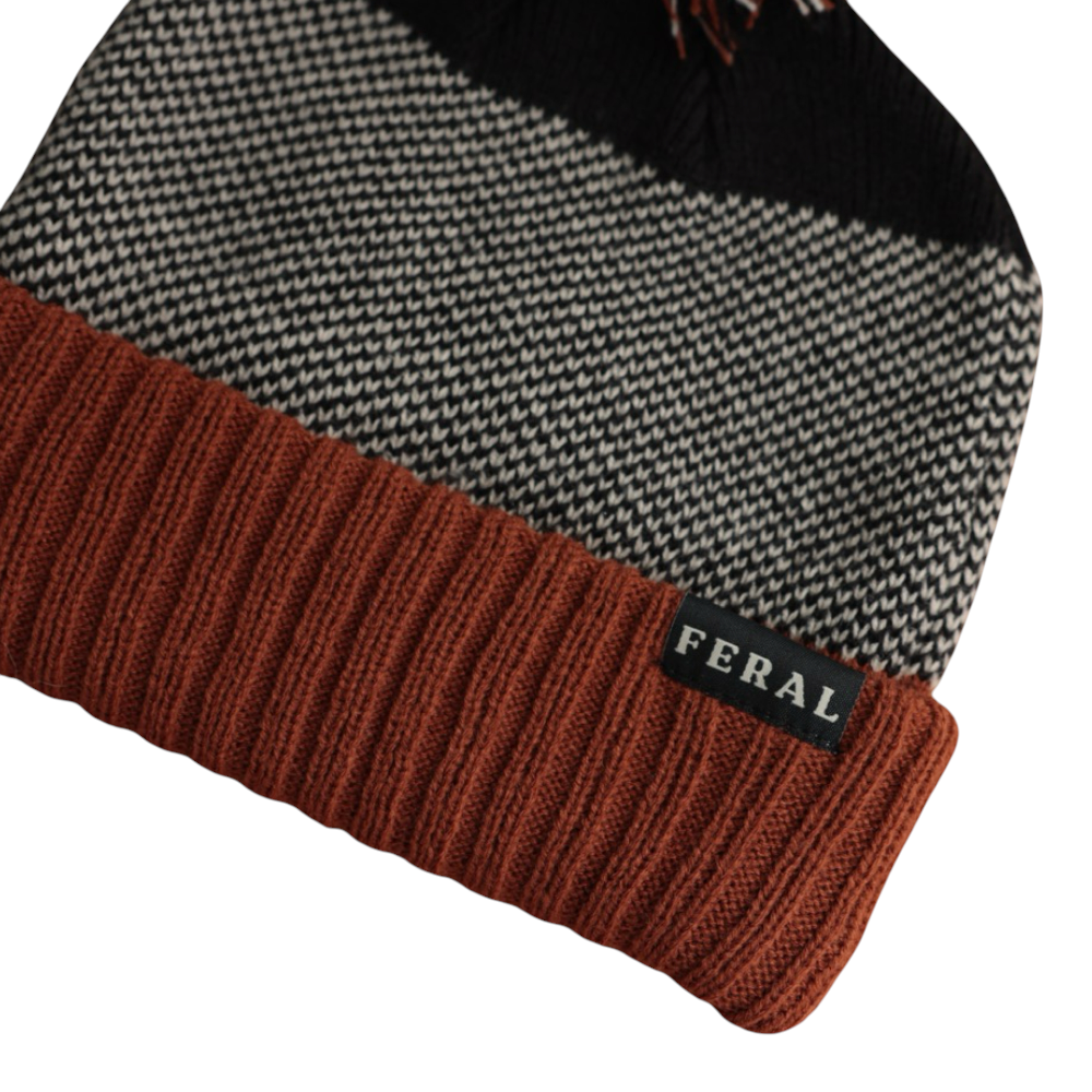 Knit beanie with a rust-colored brim by FERAL, featuring a houndstooth pattern and pom-pom.