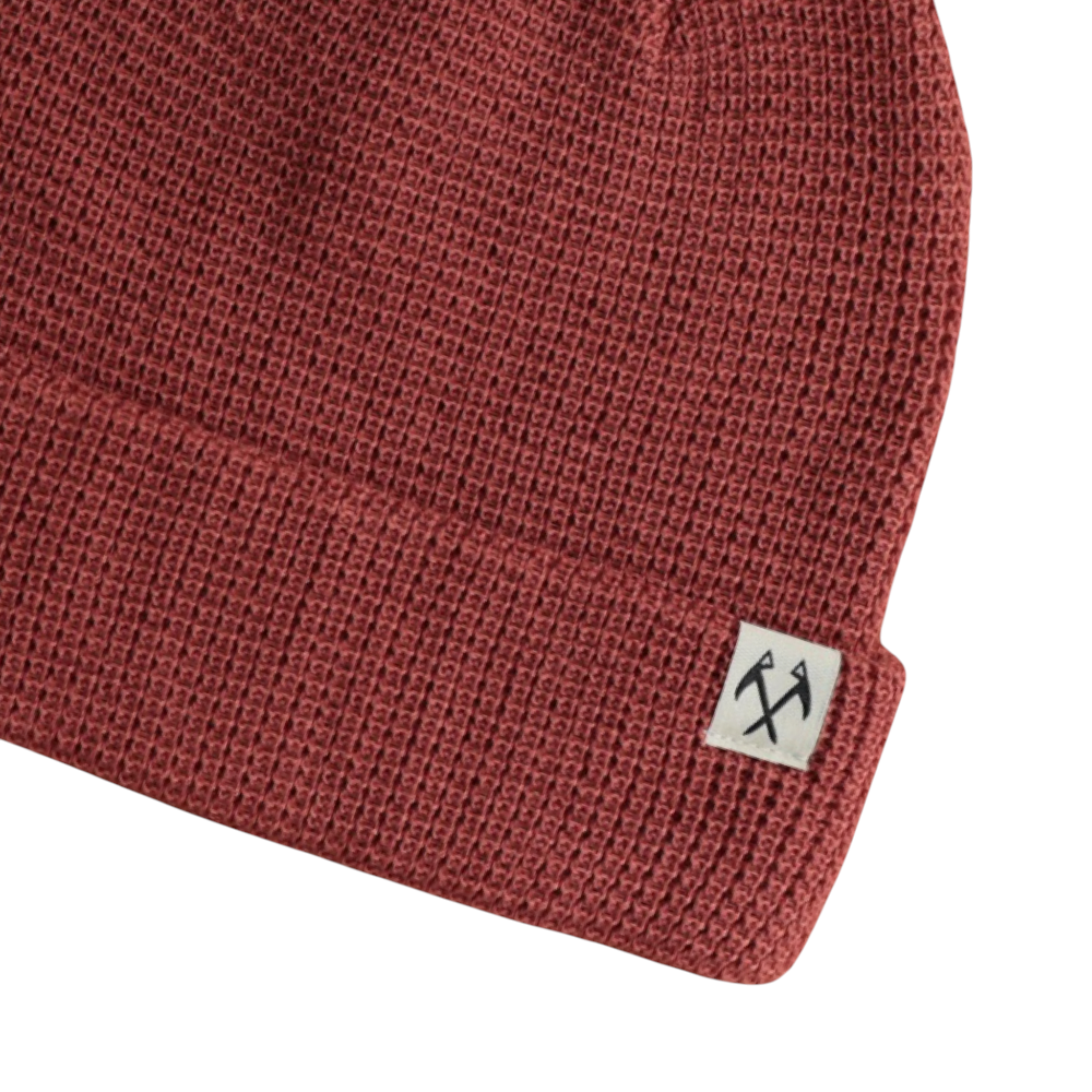 Maroon knit beanie by FERAL, featuring a waffle knit texture and a small white logo tag.