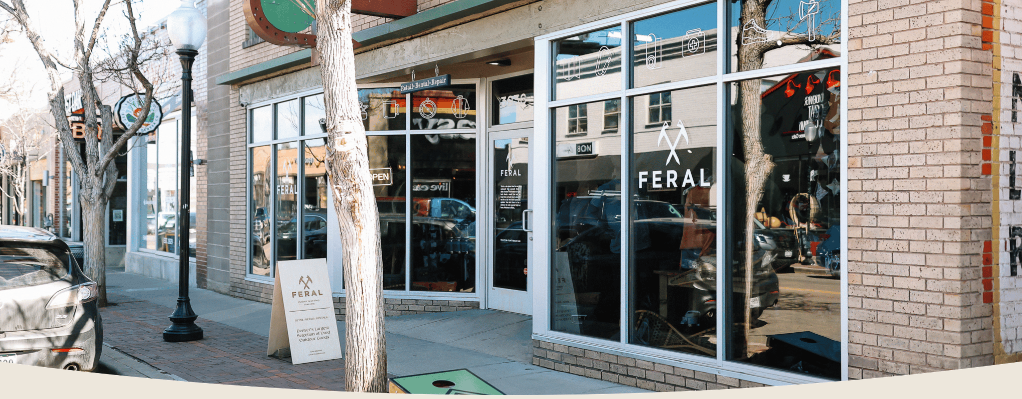 Storefront with large glass windows and a sign for 'Feral' on a city street.