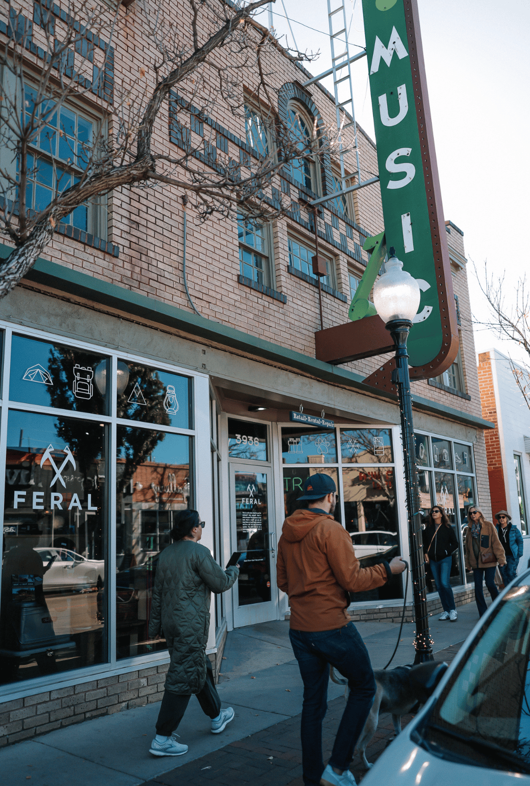 People walking in front of a store with a 'Feral' sign on a city street.