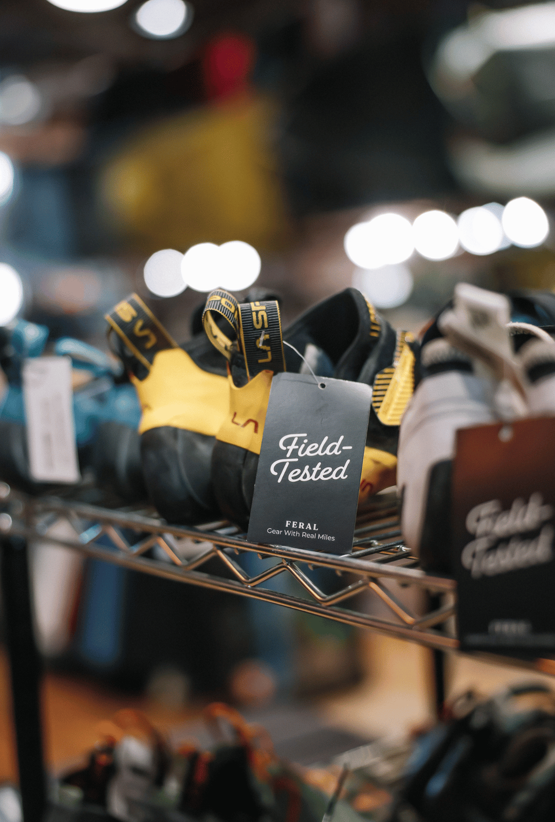 Climbing shoes on a rack with 'Field-Tested' tags in a store setting