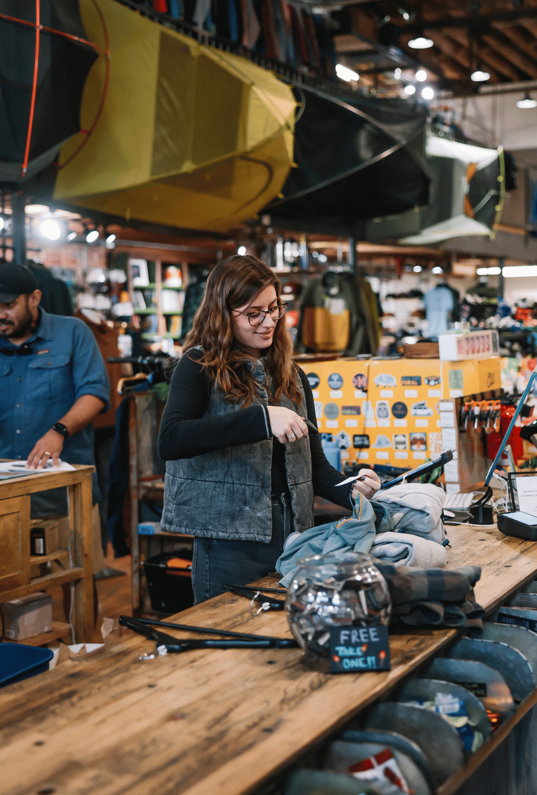 Woman in a store looking at items on a table with various products in the background
