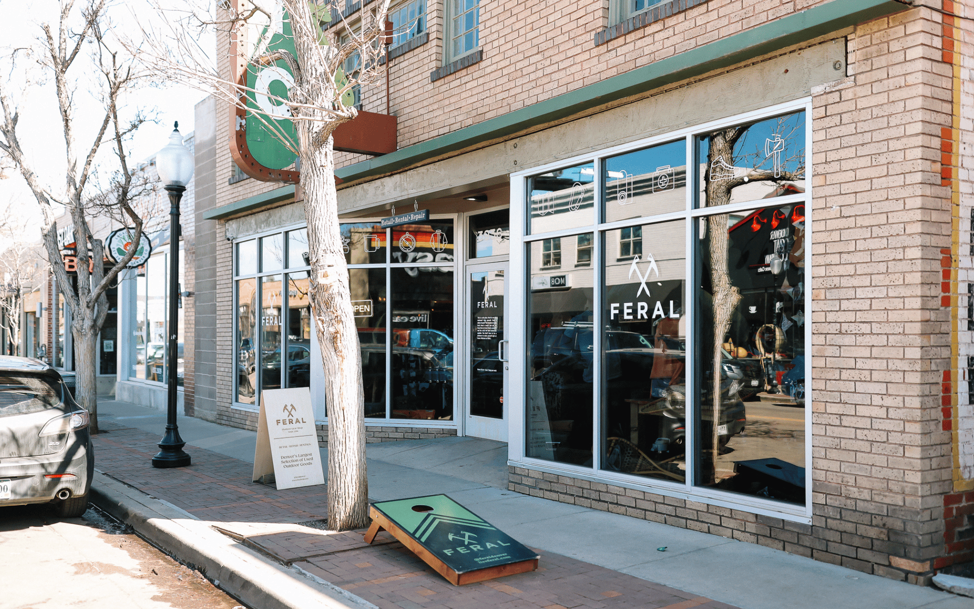 A brick building labeled "FERAL" has a storefront with large windows.