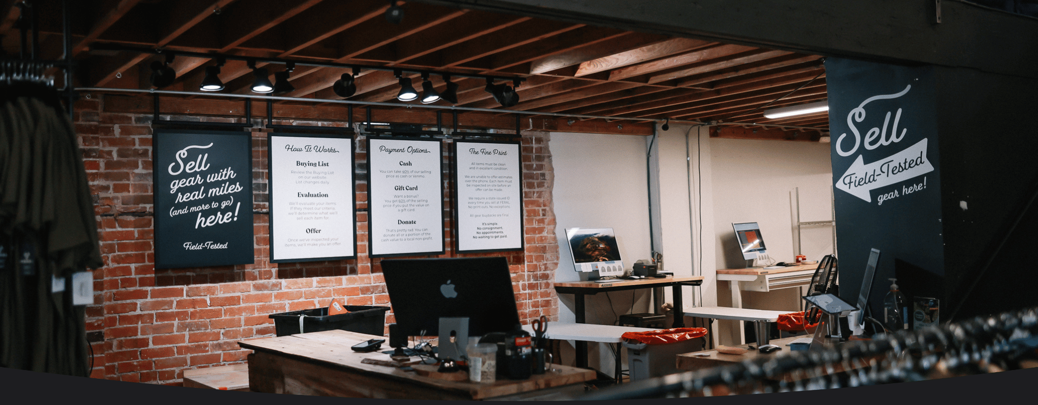 Retail space with computers and posters on a brick wall.