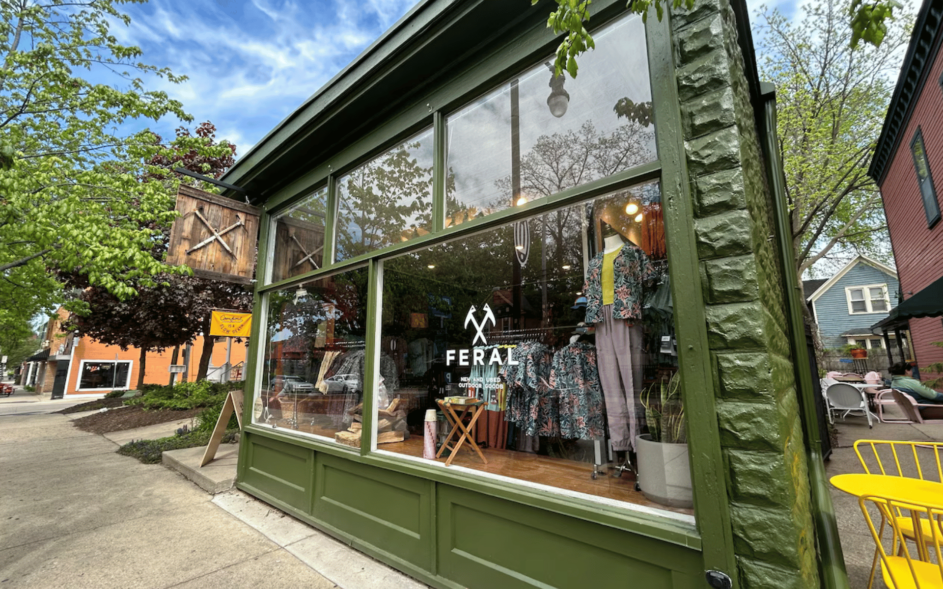 A street-level view of a green retail store called "FERAL," with clothing in the window.
