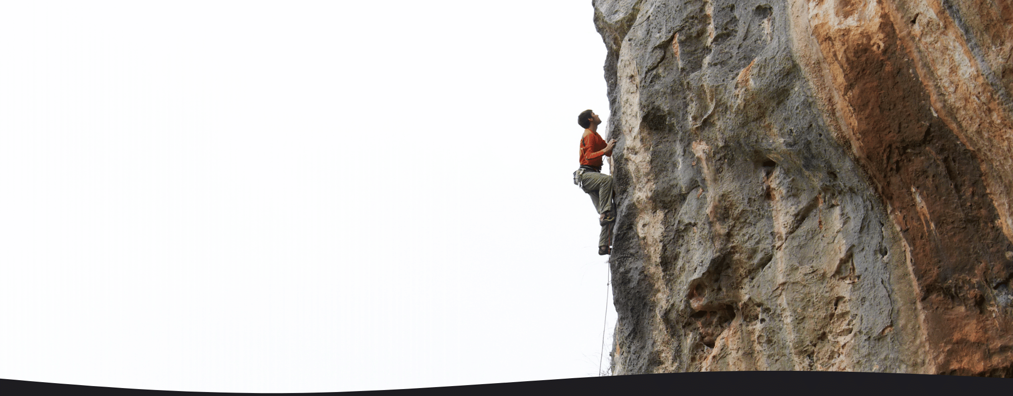 Person climbing a rocky cliff face