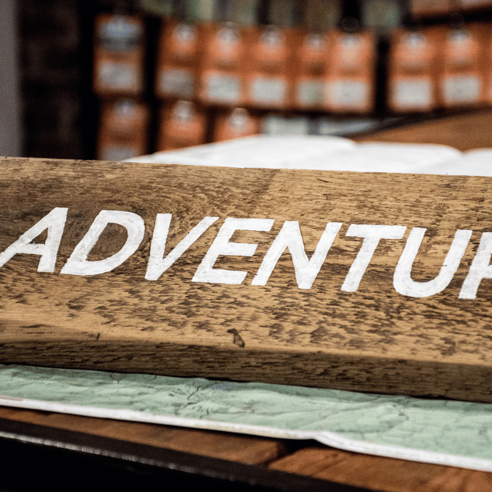 A wooden sign with the word "ADVENTURE" painted in white.
