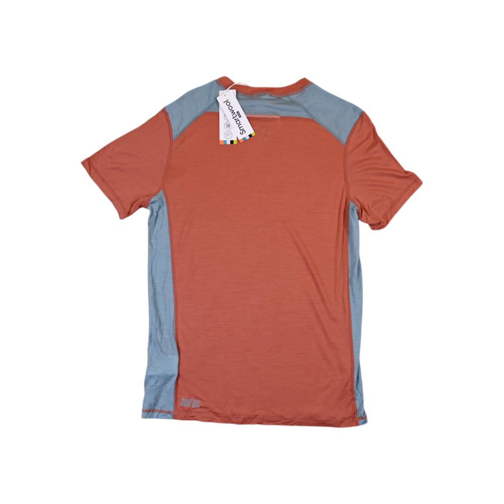 Orange tee shirt by Smartwool with gray paneling at the shoulders and side seams, featuring a paper tag.